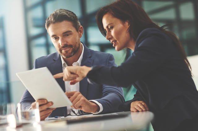 Man and woman discuss data on tablet